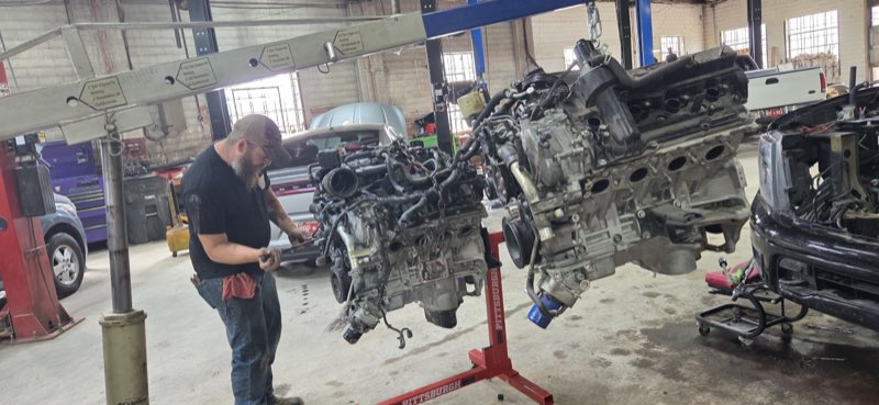 Mechanic working between two engines pulled and mounted on stands in the shop bay